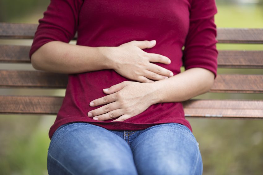 Stock image of a girl holding her stomach two hands
