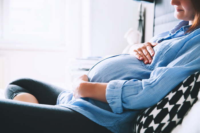 Stock image of a pregnant woman holding her stomach
