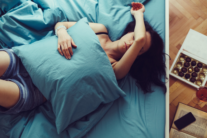 Stock image of a woman sleeping on bed feeling pain
