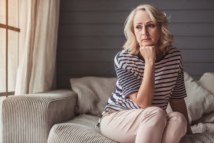 Stock image of a woman sitting and thinking by holding her chin with hand